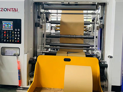 Unidad de rebobinado con cuchara de descarga que puede elevarse para proteger los rollos durante la operación