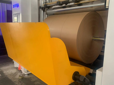 Unidad de rebobinado con cuchara de descarga que puede elevarse para proteger los rollos durante la operación